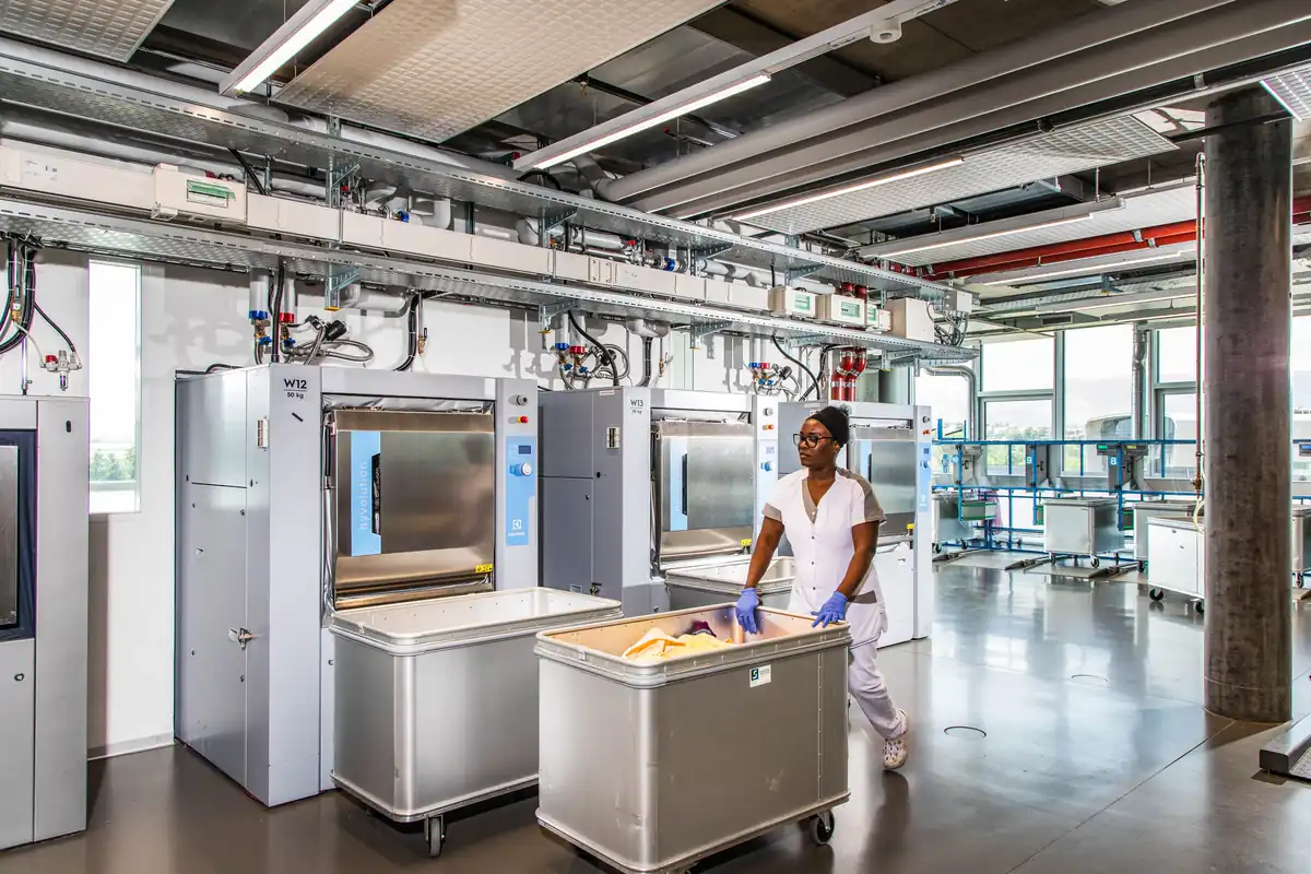 Une collègue pousse un chariot de linge dans la Blanchisserie