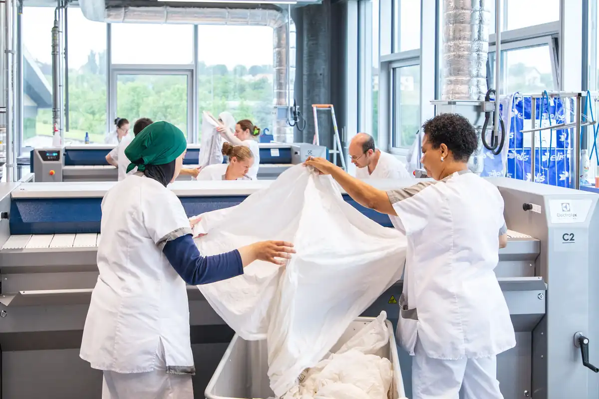 Deux collaboratrices plies du linge à la Blanchisserie